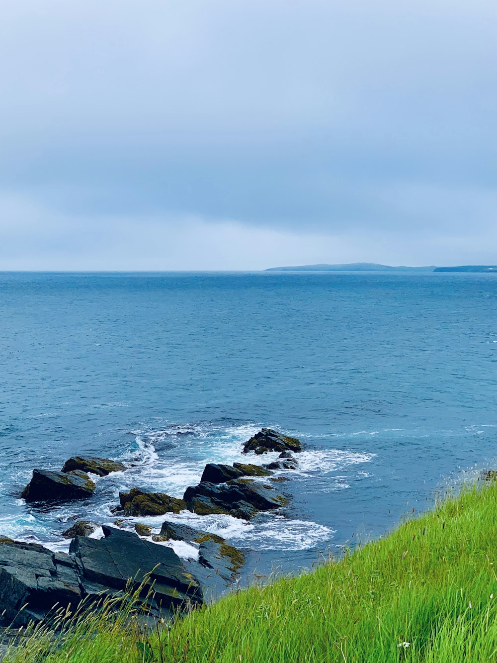 rock formations near sea under blue and white skies