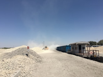 A dump truck unloading gravel at a busy construction site under a clear sky.