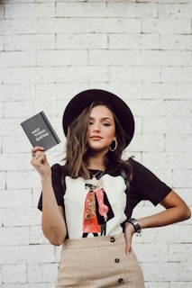 woman with left arm akimbo standing while holding leaflet