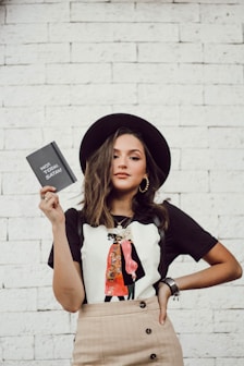 woman with left arm akimbo standing while holding leaflet