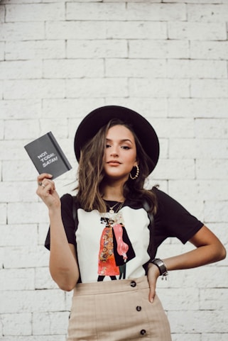 woman with left arm akimbo standing while holding leaflet