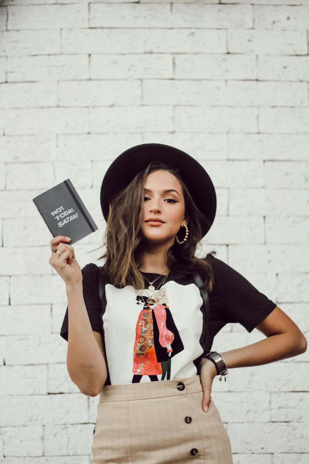 woman with left arm akimbo standing while holding leaflet