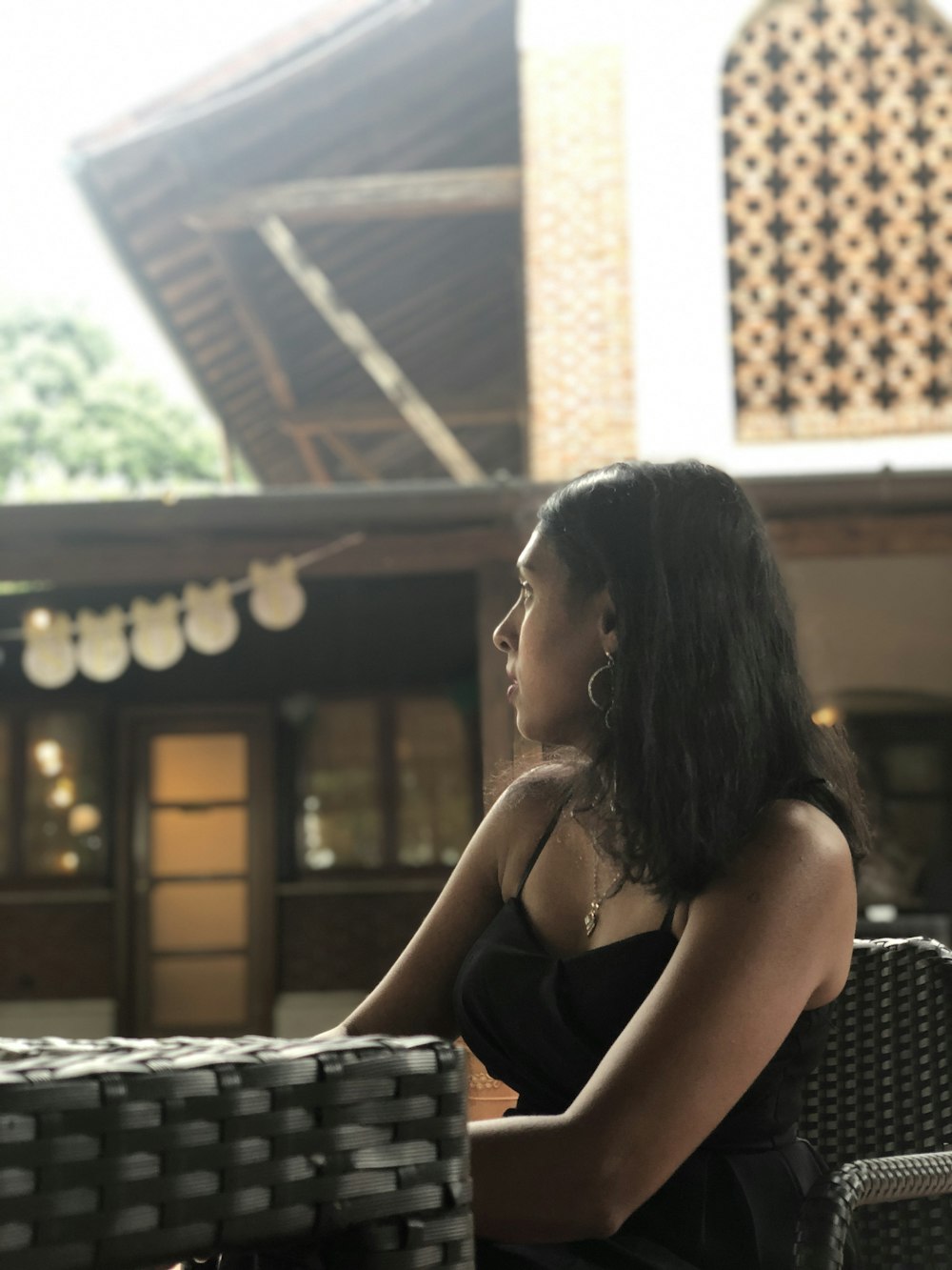 woman in black sitting on a black wicker shair