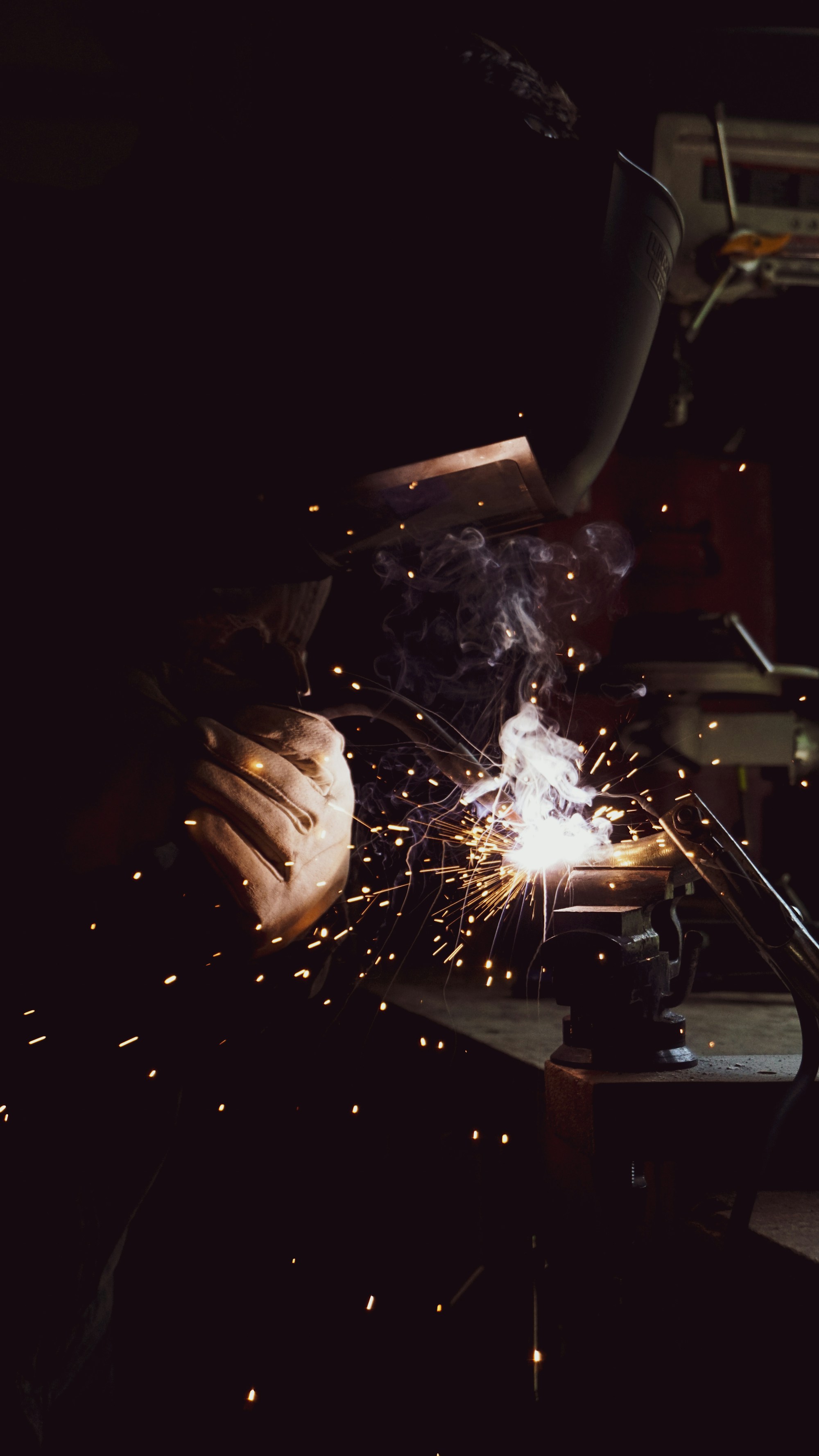 Welder working on metal with bright sparks flying