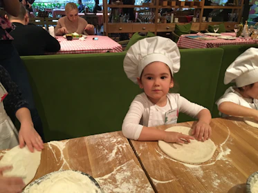 Kids happily cooking in a bright, playful minichef classroom.
