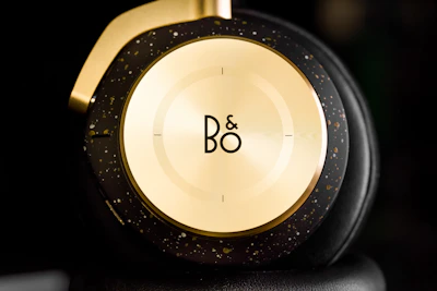 Close-up of elegant headphones resting on a black silk pillow with gold accents.