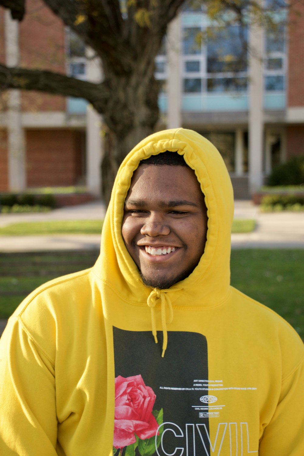 man in yellow hoodie smiling near tree