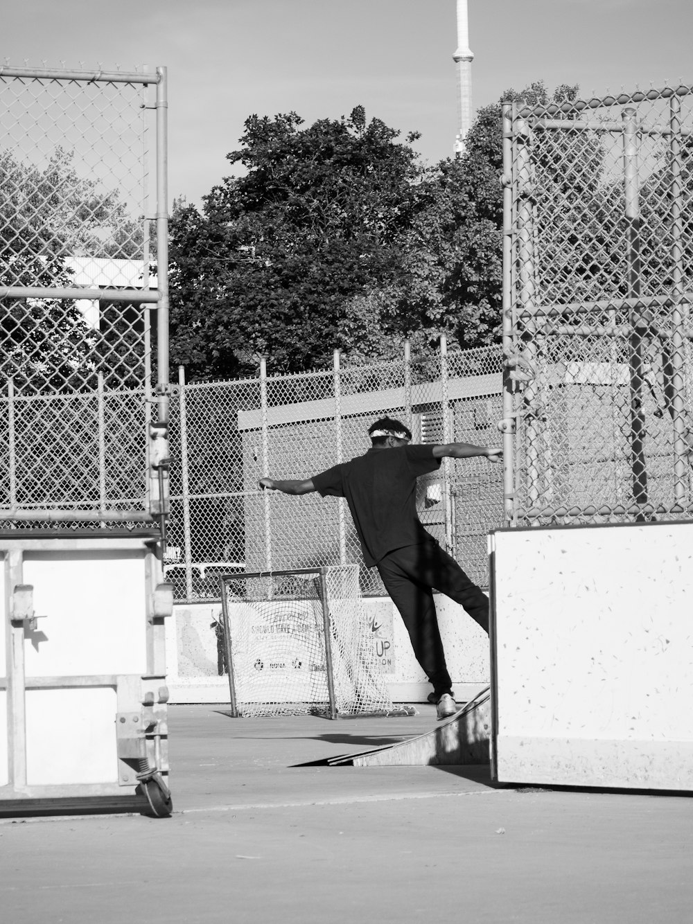 grayscale photography of man standing beside fence