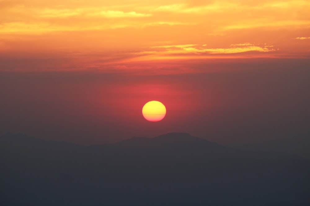 the sun is setting over a mountain range