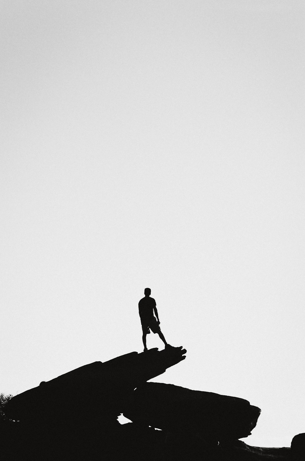 person standing in a rock formation grey-scale photography