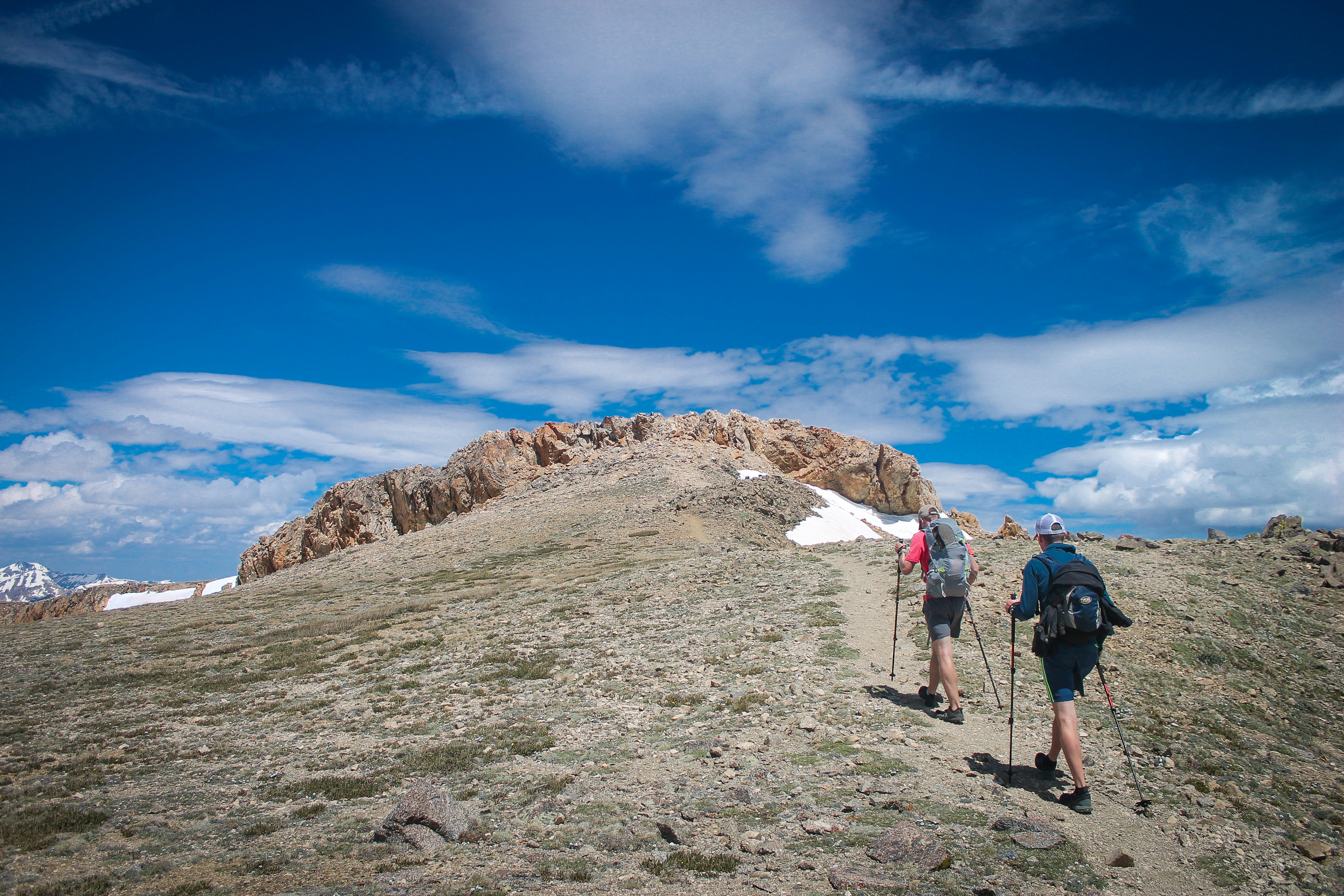 two person standing near mountain during daytime
