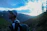 A hiker adjusting their backpack on a mountain trail during sunrise.