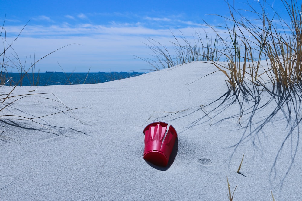 rød plastbøtte på grå sand