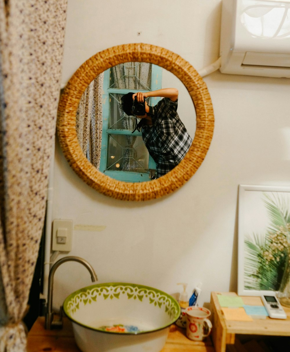 man taking photo in front of round mirror