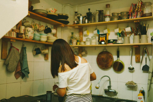 woman in white top standing beside table