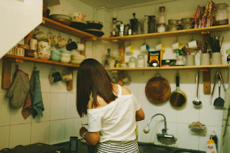 woman in white top standing beside table