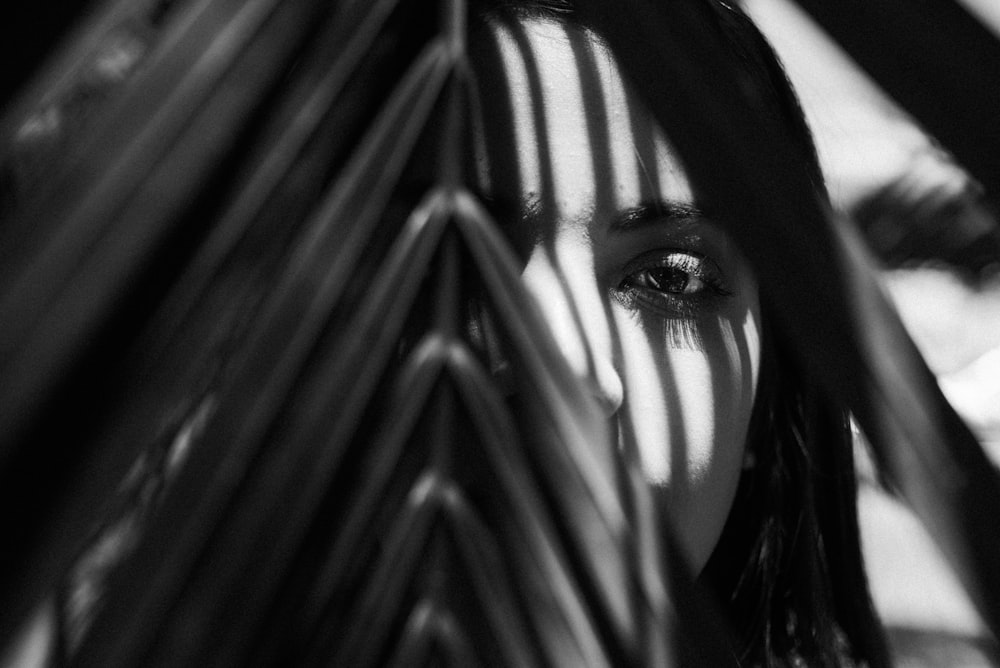 a woman's face is seen through the leaves of a palm tree