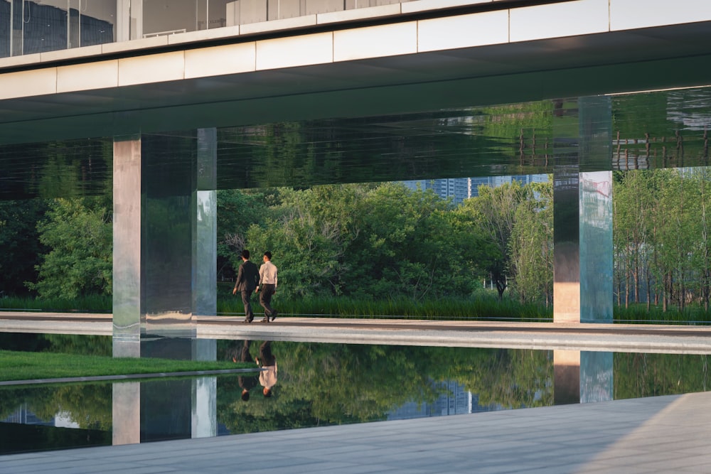 two person walking beside body of water during daytime