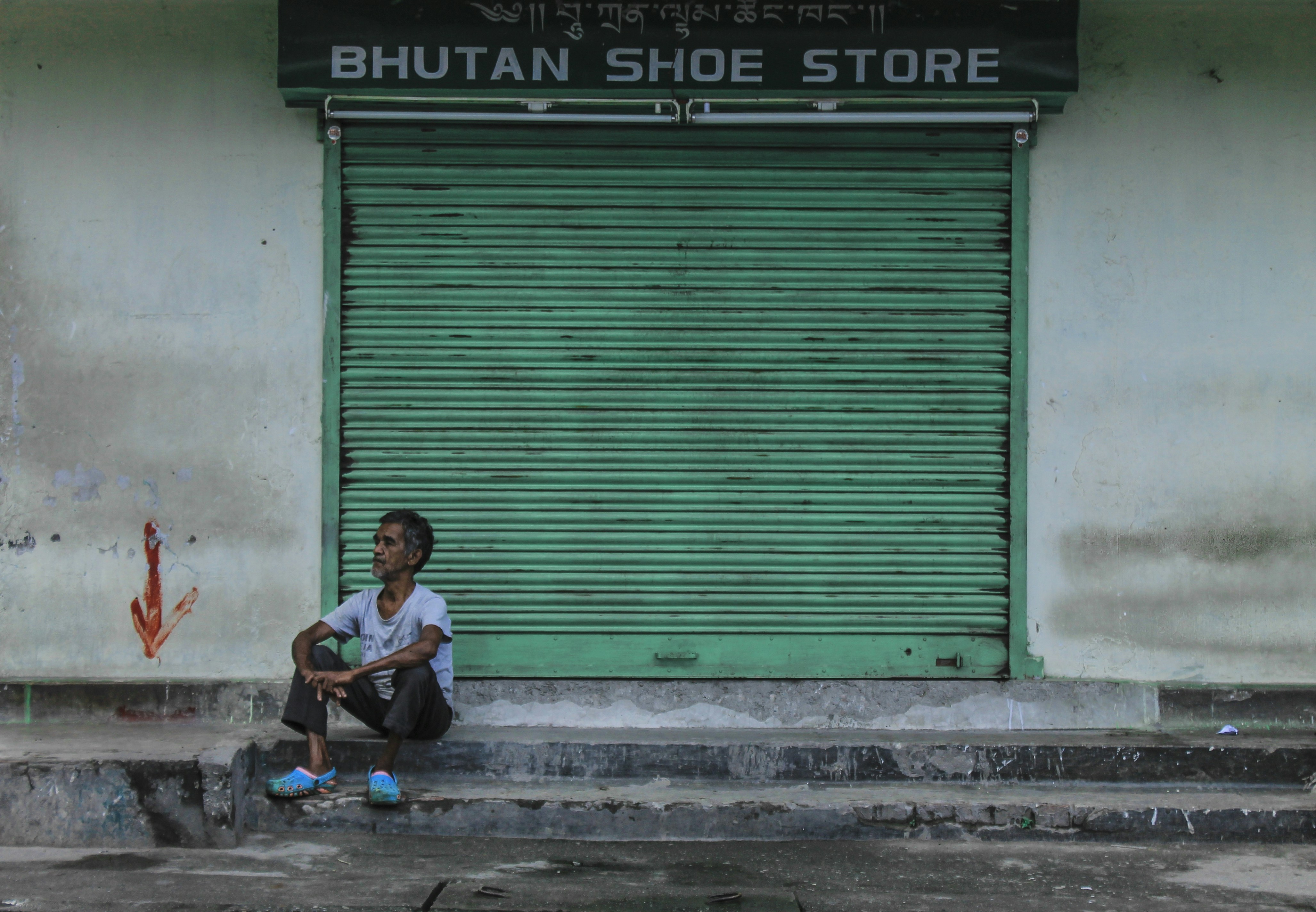 man wearing gray shirt sitting in front of Bhutan Shoe Store