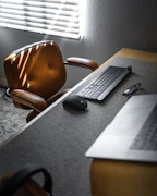 A sleek executive chair in a stylish office setting with wooden desk and laptop.