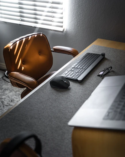 A sleek executive desk with a leather chair in a sunlit modern office.