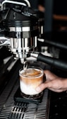 Barista carefully pouring coffee into a clear glass, highlighting crema.