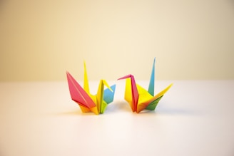 A colorful origami crane resting on a wooden table with soft natural light.