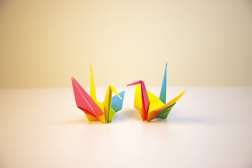 A colorful origami crane resting on a clean white background.