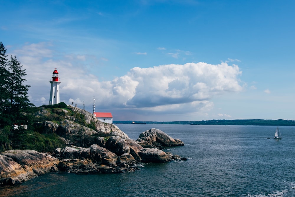 white and red lighthouse beside body of water during daytime