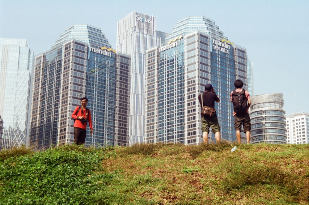 three people with glass buildings background during daytime