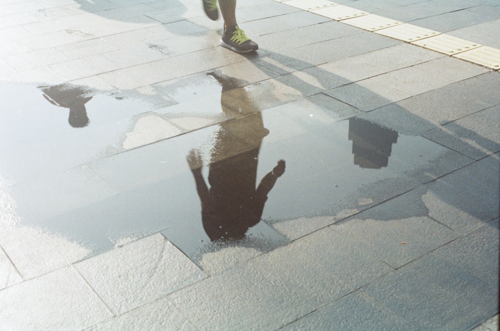 person walking on pavement near wet area