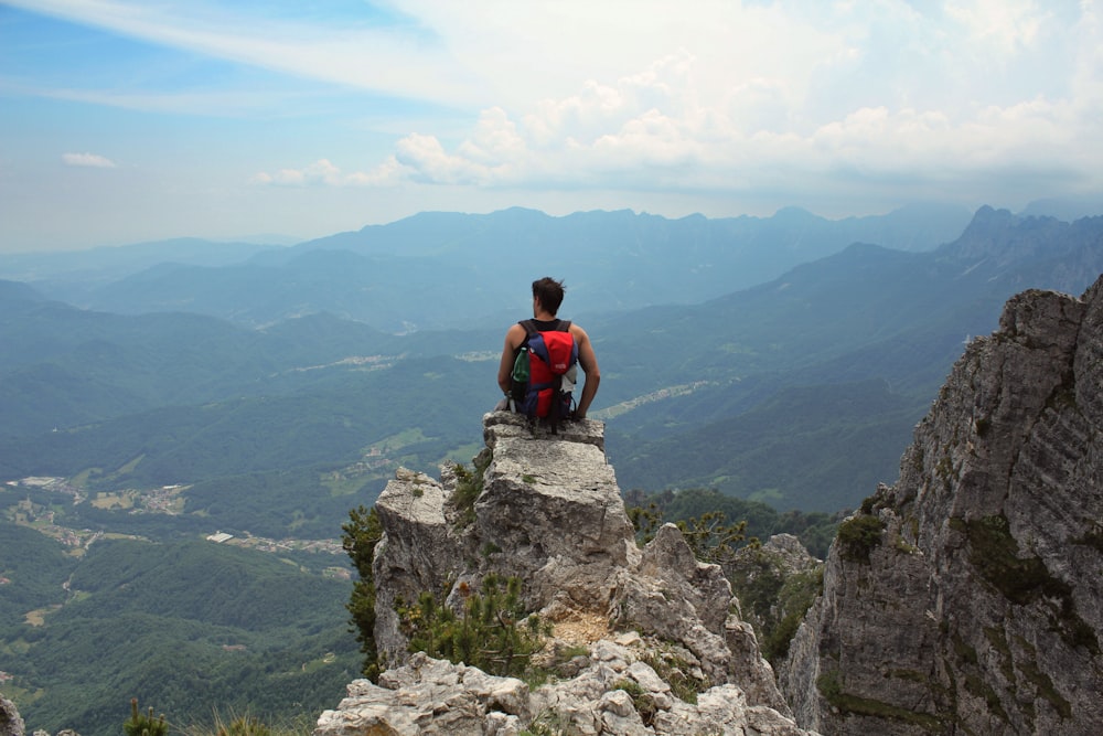 man sitting on top of cliff during daytime