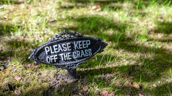 black and white please keep off the grass signage