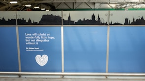 A blue panel with an inspirational quote attributed to Sir Walter Scott. Above the quote, a black silhouette of a city skyline is depicted against a lighter background.