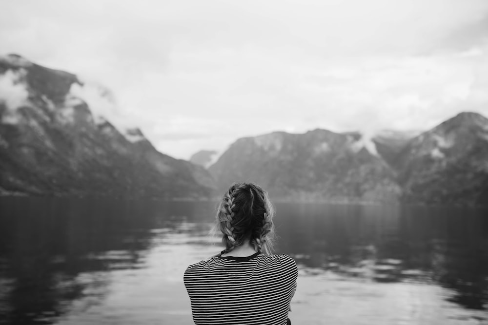 山を背景に水域を見渡す女性