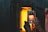 Hands holding a smartphone capturing an image of a glowing orange furnace or kiln. The scene is set in a dimly lit industrial environment, with the light from the furnace contrasting with the dark surroundings.