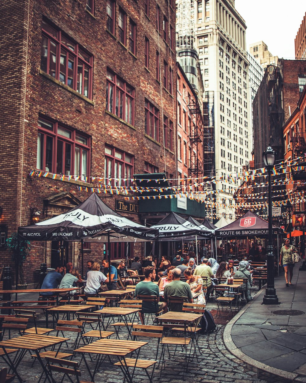 personas sentadas cerca de un restaurante junto a edificios de gran altura