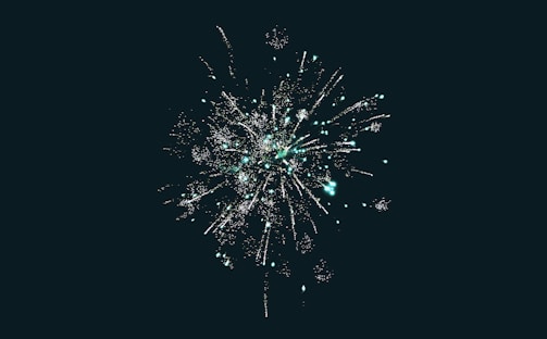 A vibrant display of fireworks exploding against a dark sky. Bright sparks radiate outward in various directions, creating a spectacle of light.