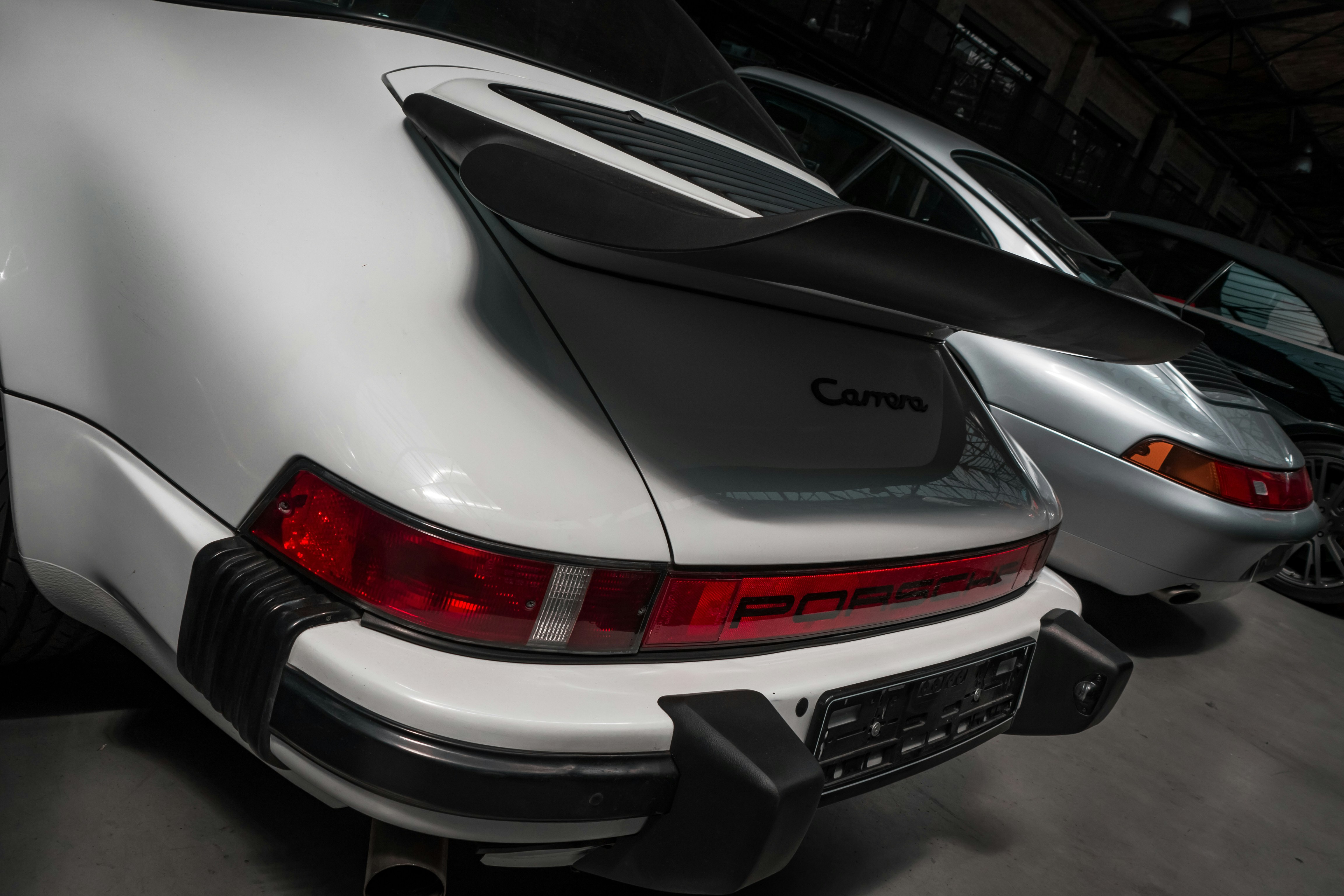 Sleek Porsche in dark garage with dramatic spotlight, deep shadows, moody automotive photography