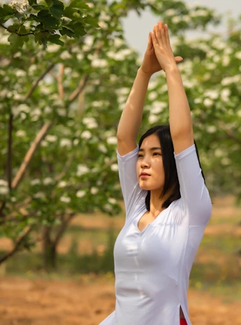 Close-up of a joyful yogi mid-pose outdoors surrounded by lush beige and green foliage.
