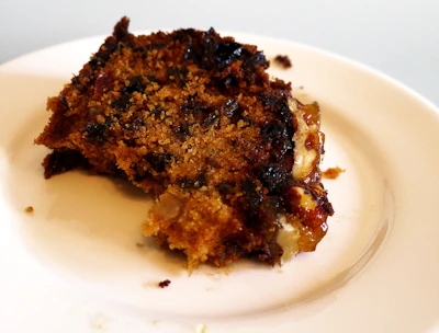 Butterscotch cake slice showing creamy layers and caramel drizzle on a rustic plate.