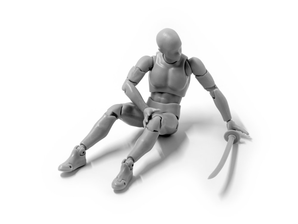 modelo humano cinza segurando katana sentado