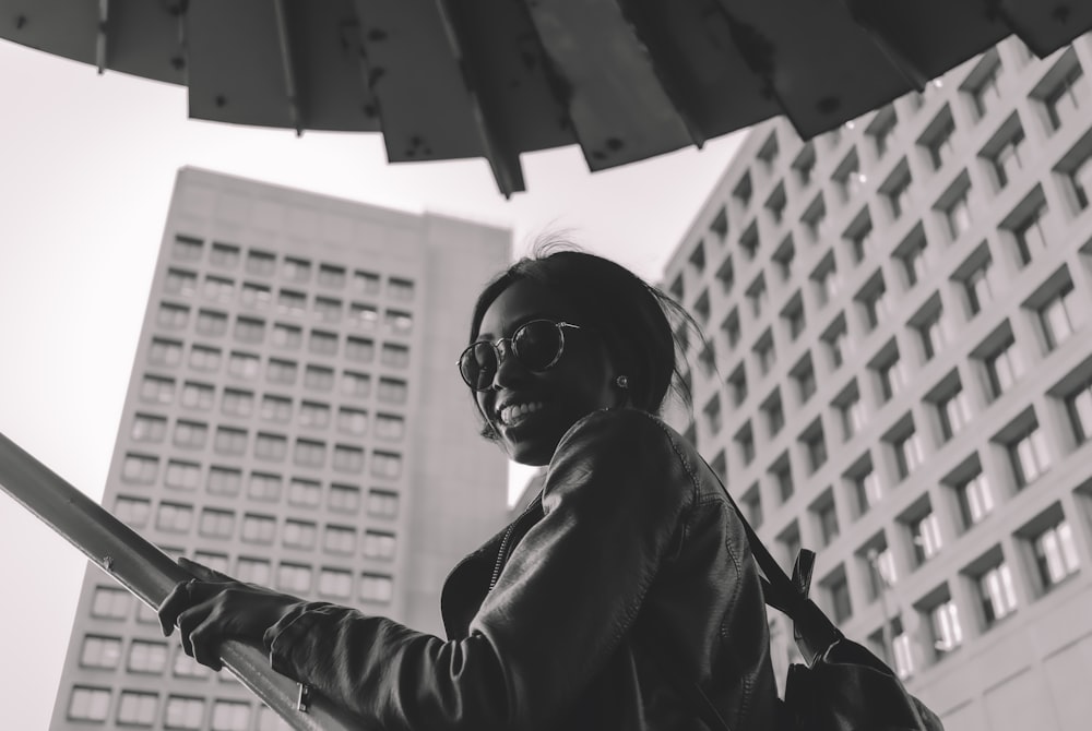 a woman holding an umbrella in front of a tall building