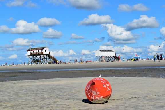 a red buoy sitting on top of a sandy beach