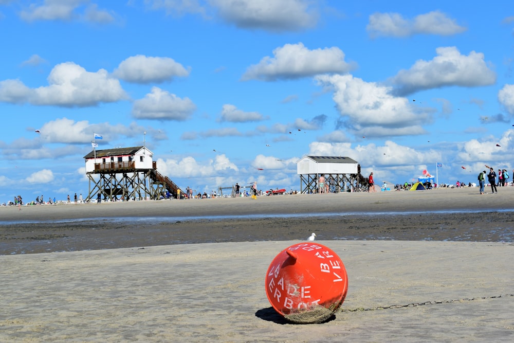 a red buoy sitting on top of a sandy beach