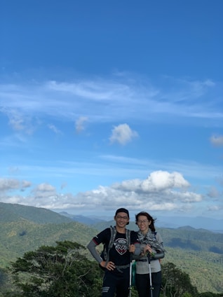 Two tour guides standing on a mountain trail with the Andes in the background, smiling warmly.