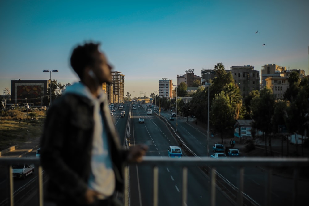 man standing and holding on gray stainless steel railings