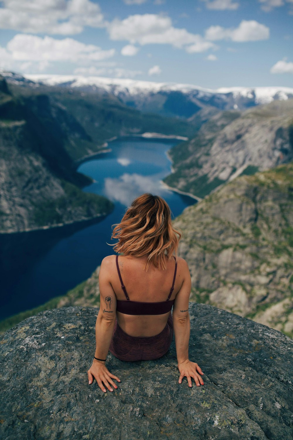 湖に面した岩の上に座る女性