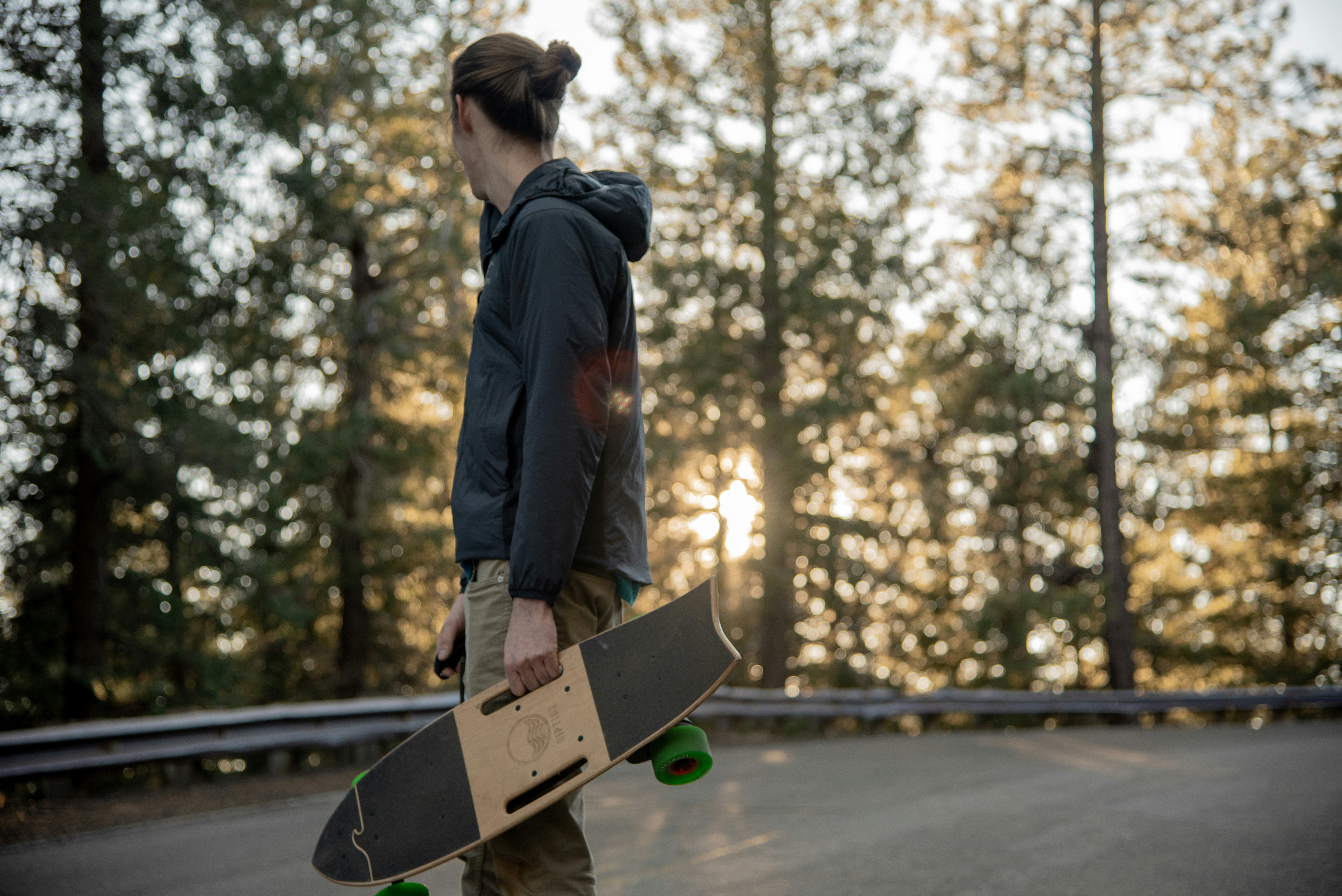 man wearing black pullover hoodie carrying skateboard