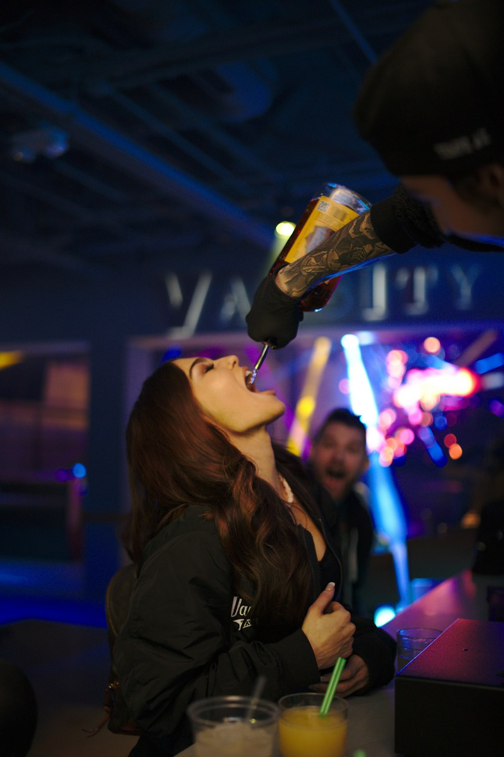 woman in black jacket using from bottle given by man